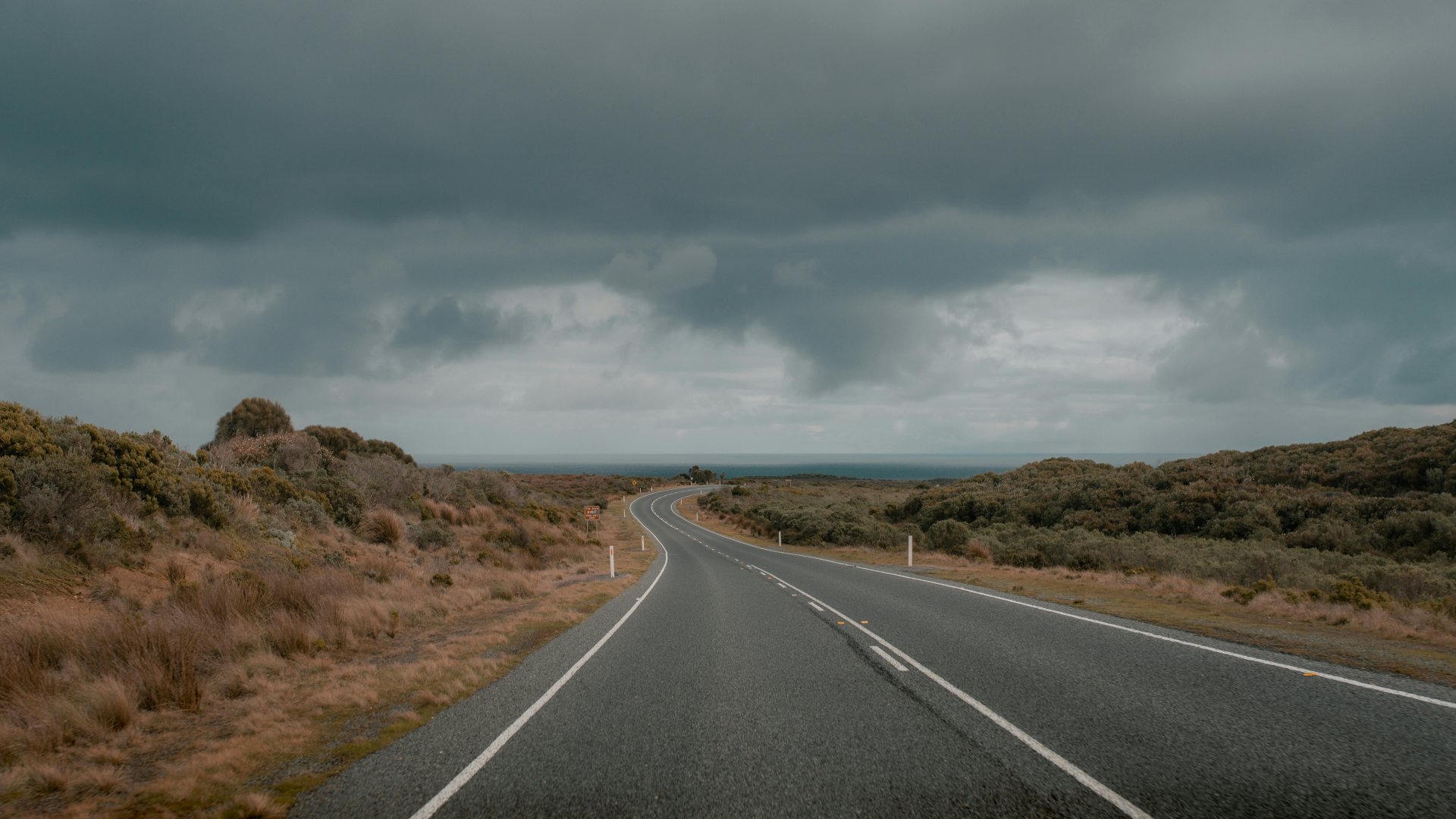 A lonely open road stretching toward the horizon under a dramatic sky