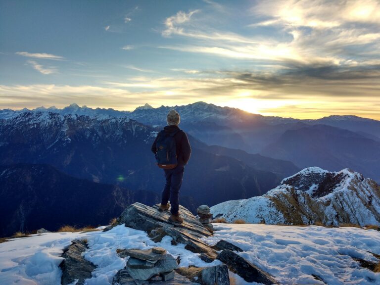 A man facing the sunrise on a mountaintop, reclaiming a new life after deep change
