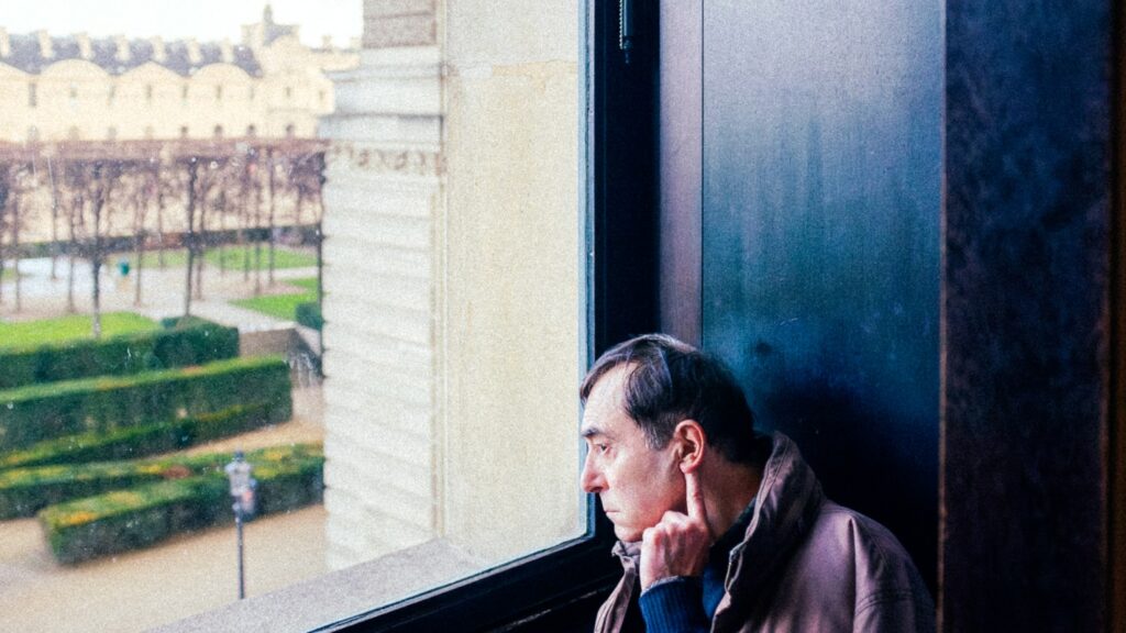 A man looking out a window toward the light, healing from a painful past with REBUILD