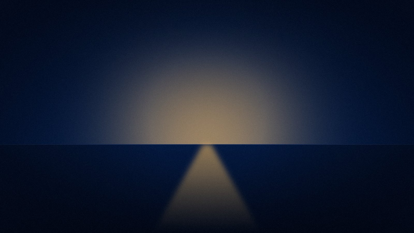A quiet navy horizon at night with a single band of warm light across the water